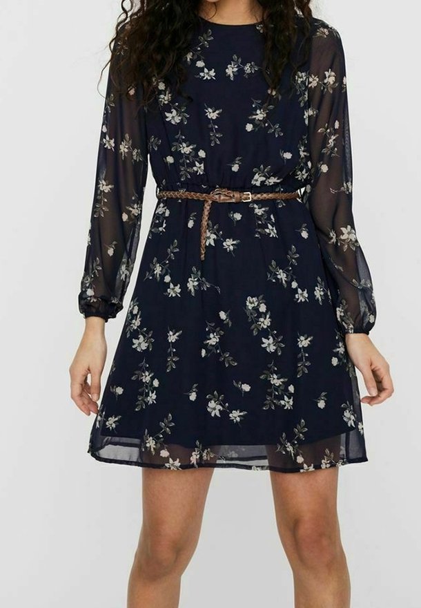 Robe florale bleu marine avec des manches longues transparentes, un ourlet volanté et une taille ceinturée. Présente des motifs de fleurs de couleur claire sur l'ensemble.