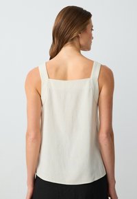 Top senza maniche beige chiaro con scollatura quadrata sul retro, realizzato in morbido tessuto, con spalline larghe e orlo arrotondato.