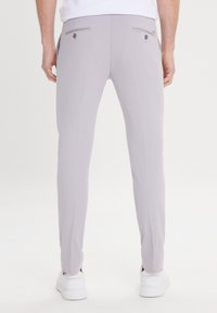 Light gray trousers with a slim fit, featuring two back pockets with buttons, paired with white sneakers. Smooth fabric with a subtle texture.