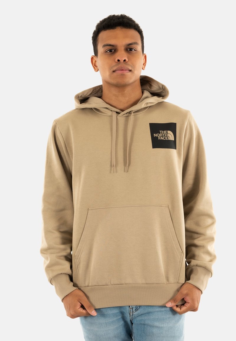 Felpa beige con cappuccio regolabile, tasca a marsupio e polsini a coste. Presenta una patch con logo nero sulla parte superiore sinistra del petto. Materiale morbido.