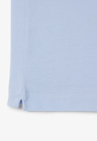 Jasnoniebieska, fakturowana tkanina z małym rozcięciem z boku, pokazująca przeszycia na podwinięciu i drobny wzór dzianiny.