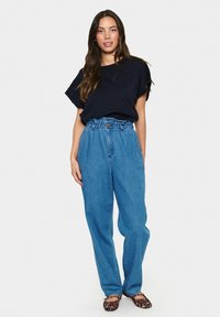 Tmavě modrý krátký rukáv s volným střihem, doplněný světlými modrými džíny s vysokým pasem. Černé a hnědé baleríny s leopardím potiskem.