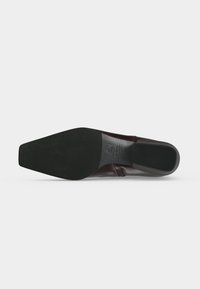 Chaussure habillée élégante à semelle noire vue par le dessous, avec un bout carré et un petit talon rectangulaire.