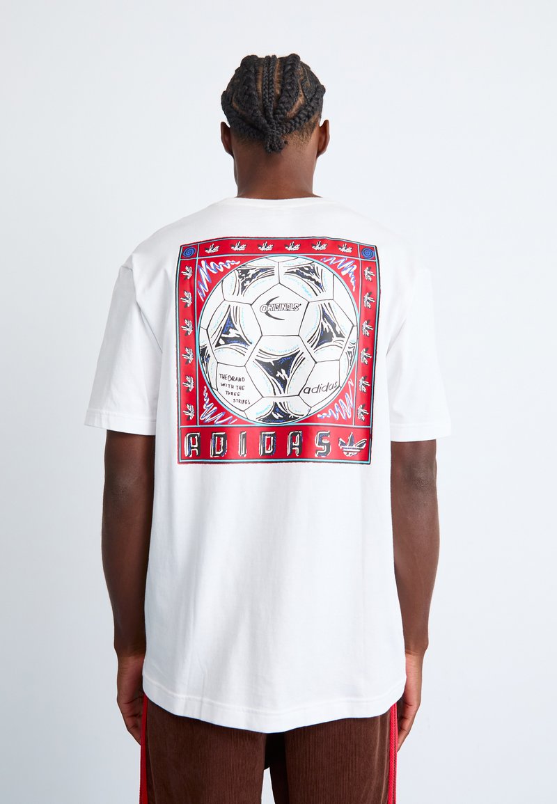 Hvid bomulds-T-shirt med en grafisk print på bagsiden, der viser en fodbold og farverige kantdetaljer. Korte ærmer; afslappet pasform.