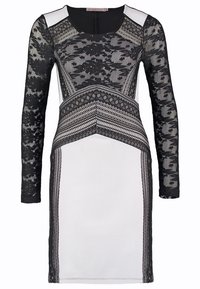 Robe blanche avec de longues manches en dentelle noire et des motifs complexes en dentelle noire sur la poitrine et la taille, créant un effet superposé.