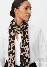 Sciarpa con stampa leopardata in beige e nero, realizzata in tessuto morbido, con una texture leggera e una vestibilità morbida intorno al collo.