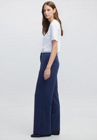 Losse navy broek met een brede pijp, elastische tailleband en zakken, gecombineerd met een eenvoudig wit T-shirt met korte mouwen.