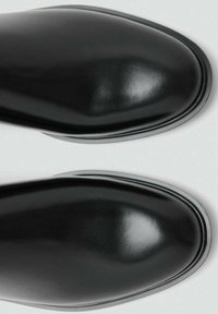 Bottes noires en cuir avec une finition brillante, bouts arrondis et texture lisse. Présente un détail de couture subtil et une semelle fine et élégante.