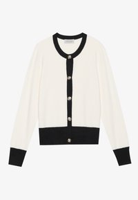 Cardigan blanc avec des accents noirs, présentant des boutons en argent et un col noir. Fabriqué en matière douce, avec des manches longues et une coupe courte.