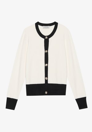 Weißer Cardigan mit schwarzen Akzenten, versehen mit silbernen Knöpfen und einem schwarzen Kragen. Hergestellt aus einem weichen Material, mit langen Ärmeln und einer cropped Passform.
