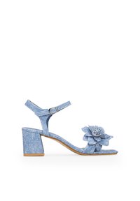 Sandalia de tacón bloque de denim con un acento floral, correa ajustable en el tobillo, punta abierta y tejido texturizado en azul. Forma de punta cuadrada.
