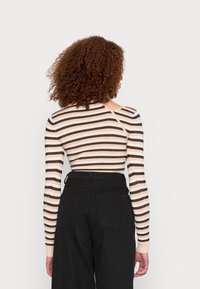 Blusa de manga longa com riscas horizontais em bege e preto, textura canelada, com um leve decote nas costas e um design ajustado.