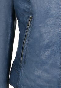 Veste en cuir bleu avec une fermeture éclair sur le côté, texture lisse et design structuré avec une légère finition brillante.