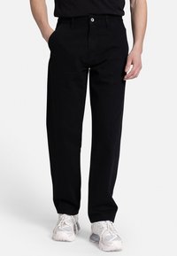 Black denim pants with a straight-leg fit, featuring front pockets, a button closure, and clean stitching. Paired with light footwear.