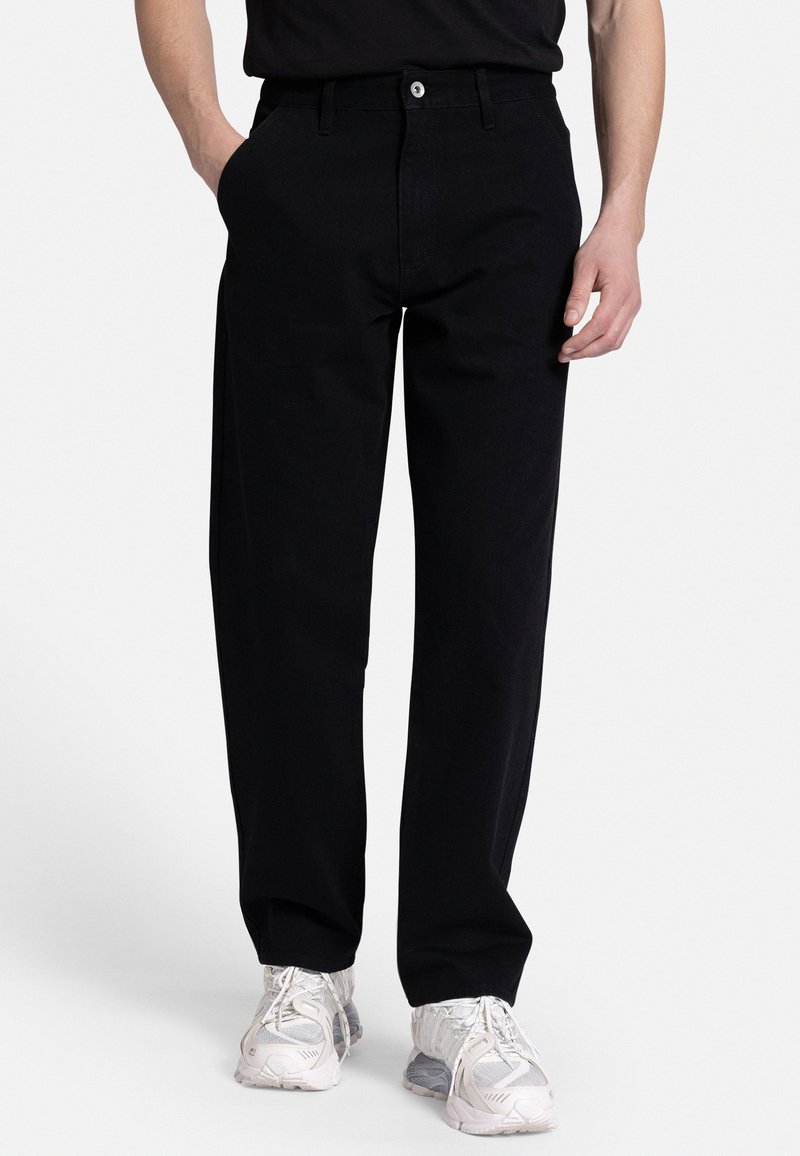 Black denim pants with a straight-leg fit, featuring front pockets, a button closure, and clean stitching. Paired with light footwear.