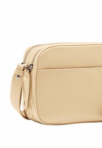 Borsa a tracolla in pelle beige con finitura testurizzata, dotata di chiusura con zip superiore e tasca frontale. Forma rettangolare compatta con tracolla.