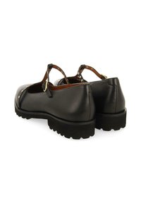 Chaussures noires en cuir avec un bout arrondi, une semelle en caoutchouc épaisse et une bride de cheville avec des accents en métal. Texture lisse avec des détails cloutés.