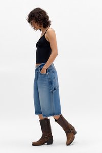 Black lace tank top, loose-fit light blue denim culottes with pockets, and brown leather ankle boots with buckles, viewed from the side.