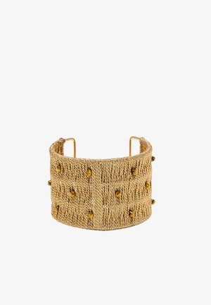 Large bracelet manchette doré avec un motif tressé texturé et de petites pierres précieuses couleur ambre.