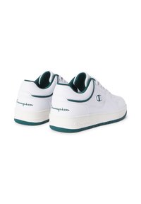 Ein Paar weiße Low-Top-Champion-Sneaker mit dunkelgrünen Akzenten, Logos an den Seiten und Fersen sowie weißen Gummisohlen vor einem weißen Hintergrund.