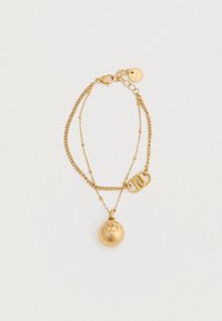 Dvojitý zlatý náramok s hladkým okrúhlym príveskom a obdĺžnikovým kúskom s prepleteným dizajnom písmen.