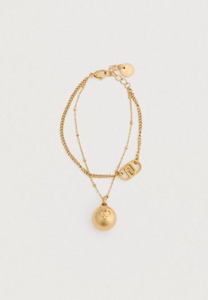 Kaksoispintainen kultaketju, jossa on sileä pyöreä riipus ja suorakulmainen viehe, joka esittelee toisiinsa kietoutuvan kirjaimen muotoilun.