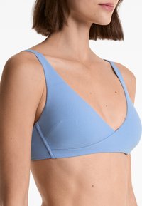 Blå randig bralette med V-ringning, breda remmar och sömlösa kanter. Texturerad tyg med subtil stretch, med rena linjer och en skräddarsydd passform.