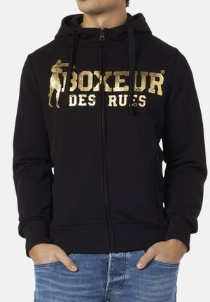 Schwarze Kapuzenjacke aus weicher Stoff, mit einem goldenen Aufdruck-Logo und Design auf der Vorderseite, mit Kordelzügen und gerippten Bündchen.