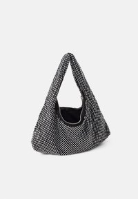 Sac noir avec des clous argentés, présentant un design décontracté, un fond arrondi et une seule poignée triangulaire. Fermeture zippée sur le dessus.