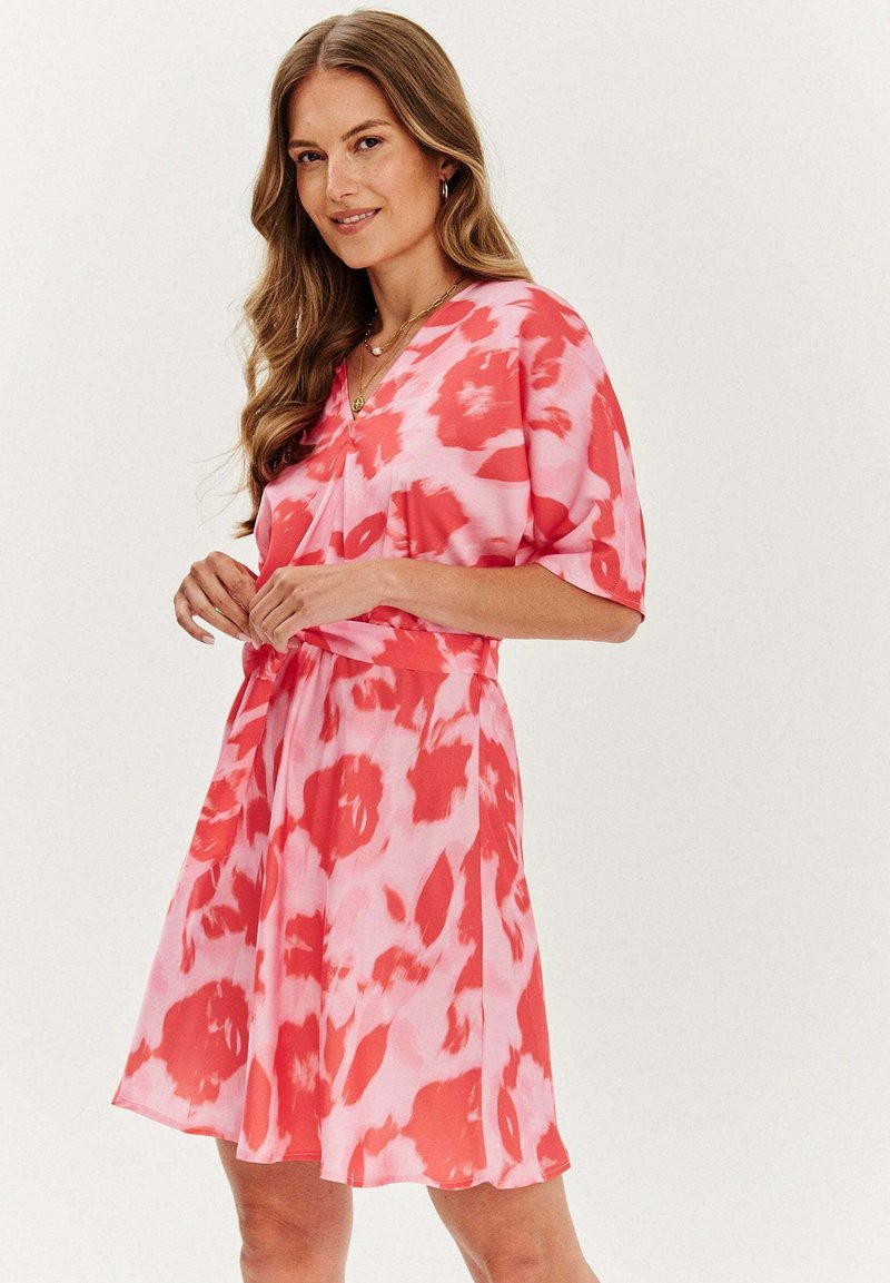 Šaty s krátkým rukávem v růžovo-červeném tie-dye vzoru, s výstřihem do V a nastavitelným páskem v pase, vyrobené z lehkého materiálu.