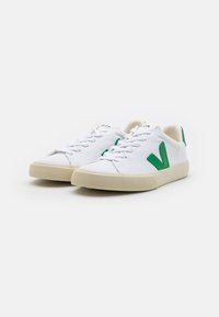Sneaker bianche in tela con logo V verde in gomma, punta rotonda, design con lacci e suola in gomma crema texturizzata.