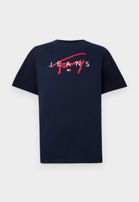 Námornícky modré bavlnené tričko s krátkymi rukávmi, s červeným preškrtnutým nápisom "Jeans" a malým bielym logom v spodnej časti uprostred.