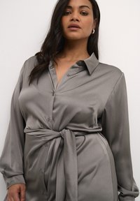 Graues, knöpfbares Hemdkleid aus glattem Stoff mit strukturiertem Muster, mit tailliertem Gürtel und langen Ärmeln, lässigem Kragen.