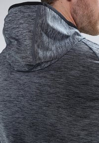 Dunkelgrauer Sporthoodie mit meliertem Textur, weichem Stoff und kontrastierendem schwarzen Saum an der Kapuze und den Schultern.