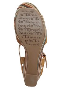 Suola di sandalo marrone che mostra una suola in gomma testurizzata con il nome del marchio stampato in rilievo e cinturini in tessuto a righe colorate con motivi multicolori.