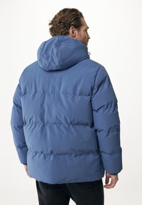 Modrá péřová bunda s kapucí, s prošívaným designem a elastickými manžetami. Materiál se zdá hladký a lehký.