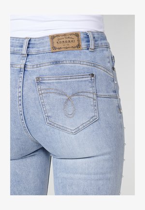Lichtblauwe denim jeans met een gestikt achterzakontwerp en een leren label. Decoratieve parels langs de zijkant.