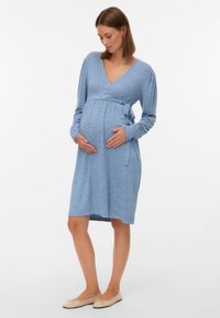 Jasnoniebieska, dzianinowa sukienka ciążowa z kopertowym fasonem, długimi rękawami, wiązaniem w pasie i długością do kolan. Miękka tekstura z subtelnym wzorem.