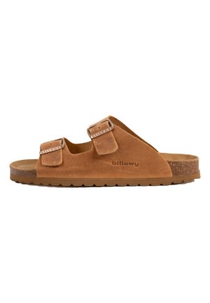 Sandale à glissière en suede marron avec deux sangles ajustables, semelle en liège et semelle intérieure texturée. Nom de la marque "billowy" embossé sur le côté.