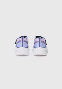 Une paire de sneakers dégradées en violet et rose avec des semelles blanches, vues de derrière sur un fond clair et uni.
