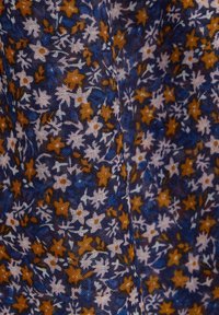 Tela impresa con un fondo azul oscuro y pequeños patrones florales en naranja y blanco. La textura parece ligera y ligeramente transparente.