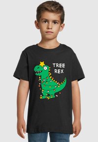 Juodas marškinėliai su žaliu animaciniu dinozauru, kuris turi girliandas ir žvaigždę ant galvos, užrašas sako "TREE REX." Trumpomis rankovėmis, pagaminti iš medvilnės.