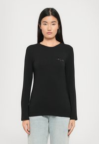 Schwarzes Langarmshirt aus glattem Stoff mit Rundhalsausschnitt und kleinem gestickten Logo auf der Brust.