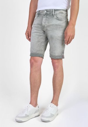 Lichte grijze denimshorts met opgerolde zoom, voorzien van een knoopsluiting, vijf zakken en subtiele vervaging. Draagt met witte sneakers.