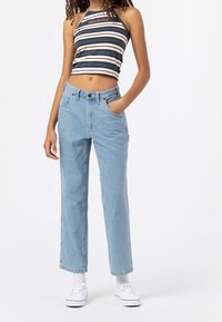 Světle modré džíny z denimu s uvolněným střihem, vysokým pasem a předními kapsami, doplněné černobílým pruhovaným crop topem.