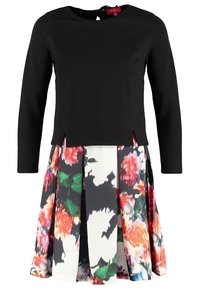 Svart långärmad topp med rund halsringning, matchat med en blomtryckt kjol med rosa, gröna och svarta inslag. Delad fåll.