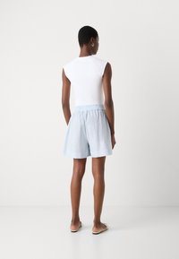 Witte mouwloze top gecombineerd met lichtblauwe gestreepte shorts met een elastische tailleband, een gladde textuur en een losse pasvorm.