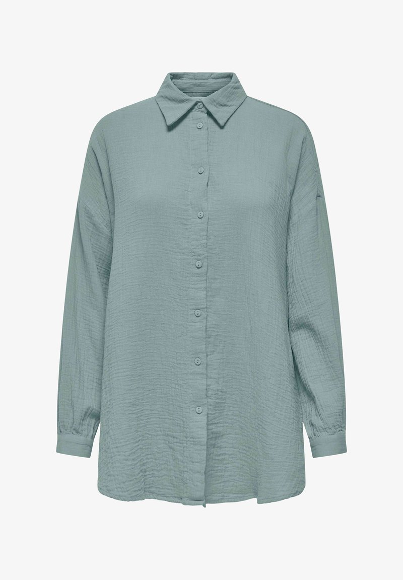 Chemise à manches longues, boutonnée, de couleur vert sauge clair avec un tissu texturé et un col pointu, présentée sur un fond blanc.
