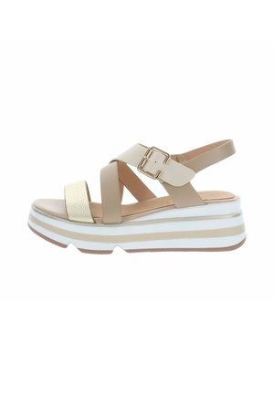 Sandale à plateforme beige et or avec des lanières croisées, une boucle dorée et une semelle rayée blanche et beige.