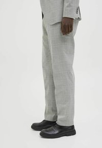 Világosszürke kockás nadrág, egyenes szabással, fekete bőr dress shoe-kal kombinálva, lekerekített orral és texturált talppal.